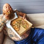 tuk na bruchu, tučný lenivý muž je pizzu na gauči